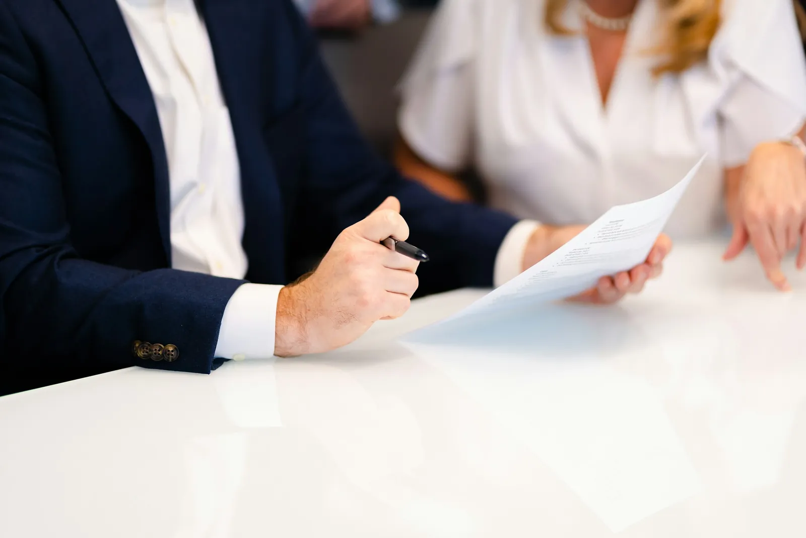 Deux professionnels relisant un document ensemble autour d’une table blanche